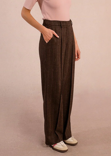 Person wearing brown striped pants on a plain background