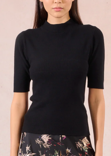 Person wearing a black top and floral skirt against a beige background