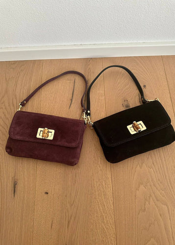 Two velvet handbags, one red and one black, on a wooden floor.