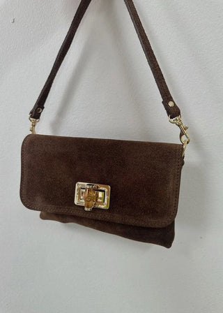 Brown suede handbag with a gold clasp on a white background